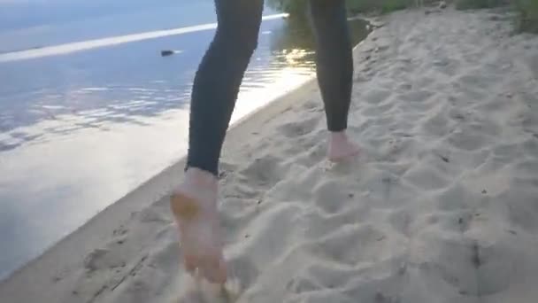 Un joven atleta corre en la playa al atardecer. Chica atlética haciendo deportes en la calle — Vídeos de Stock