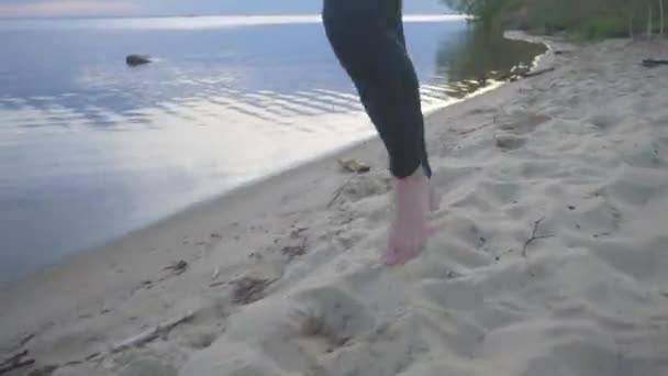 一个年轻的运动员日落时在海滩上跑步。在街上做运动的女运动员 — 图库视频影像