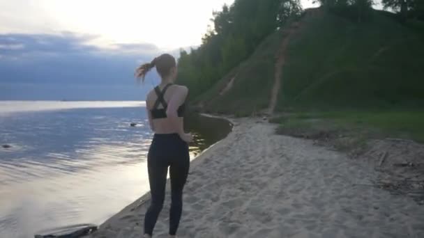 健康的女人在海滩上奔跑，女孩在户外做运动，健身和健康护理的概念，具有自然背景的复制空间 — 图库视频影像