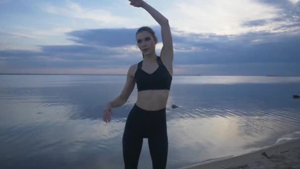 젊은 운동 선수 가 해변에서 스트레칭을 합니다. 옥외에서 운동하는 운동 선수 소녀 — 비디오