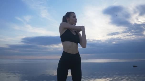 젊은 운동 선수 가 해변에서 스트레칭을 합니다. 옥외에서 운동하는 운동 선수 소녀 — 비디오
