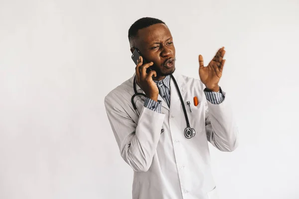 Un jeune médecin noir afro-américain en blouse blanche parle au téléphone. isolé — Photo