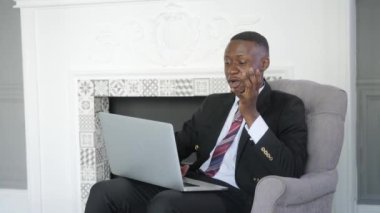 Genç siyahi iş adamı video görüşmesiyle iletişim kuruyor. Laptop bilgisayarına bakan etnik işadamı konuşması, online konferans ofis sohbeti, sanal eğitim kavramı.