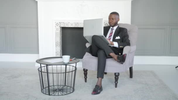 Uvolněný seriózní tisíciletý africký etnik student na volné noze pomocí notebooku zařízení, soustředěný smíšený závodní podnikatel pracující distančně psaní na notebooku v bytě — Stock video