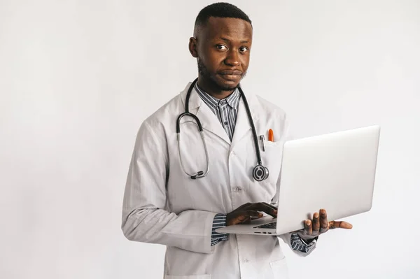 Czarny skóra młody medyk uśmiecha się stojąc na białym tle z laptopem w jego rękach — Zdjęcie stockowe