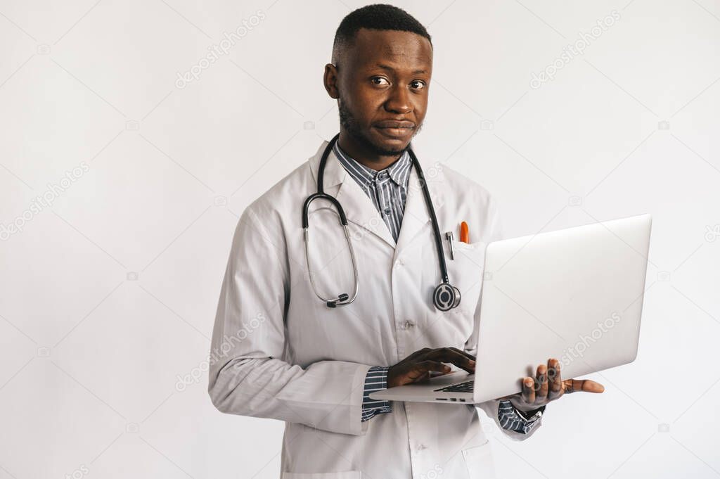 black skinned young medic smiling standing on a white background with a laptop in his hands