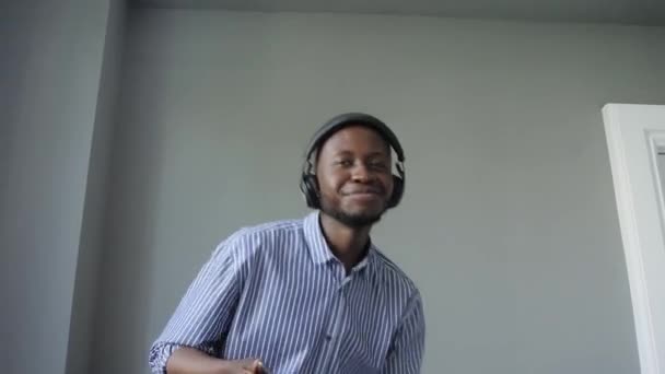 En afroamerikansk man lyssnar på musik med hörlurar och danser. Att lyssna på musik och sjunga med — Stockvideo