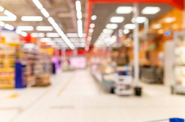 Renkli rafları ve tanınmayan müşterileri olan soyut bulanık süpermarket koridoru