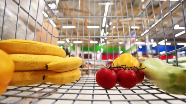 Supermercado com uma cesta de compras com legumes e frutas na cesta — Vídeo de Stock
