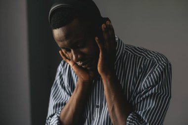 Genç Afrikalı adam kablosuz kulaklıkla müzik dinliyor ve evde dans ediyor.