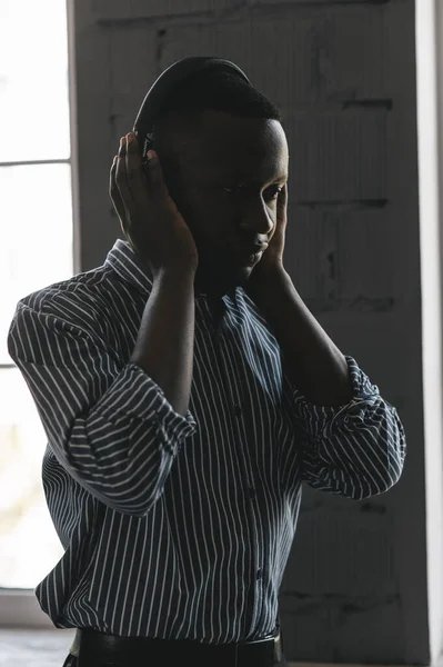Hombre afroamericano en camisa elegante en auriculares escuchando música y disfrutando de la música, bailando — Foto de Stock