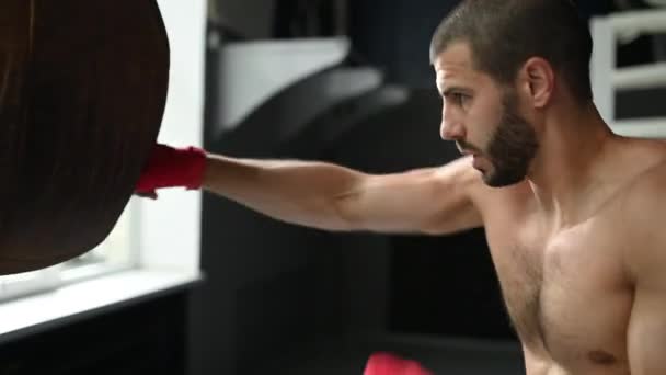 Combatiente practicando algunas patadas con saco de boxeo. Patada, saco de boxeo sobre fondo oscuro. saco de boxeo negro pesa en el gimnasio — Vídeo de stock