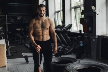 Gözleri kapalı yakışıklı vücut geliştirici spor salonunda balyoz egzersizi yaptıktan sonra dinleniyor. Tam uzunlukta kenar görünüm fotoğrafı