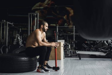 Gözleri kapalı yakışıklı vücut geliştirici spor salonunda balyoz egzersizi yaptıktan sonra dinleniyor. Tam uzunlukta kenar görünüm fotoğrafı