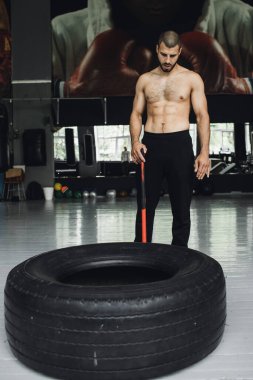 Gözleri kapalı yakışıklı vücut geliştirici spor salonunda balyoz egzersizi yaptıktan sonra dinleniyor. Tam uzunlukta kenar görünüm fotoğrafı