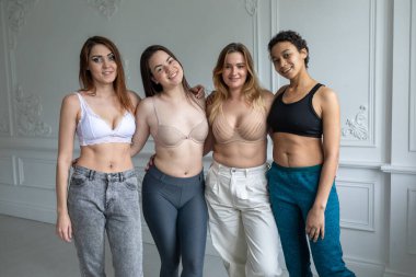 Dört farklı etnik kökenden mutlu güzel kız arkadaş. Çemberde uzanan kadın arkadaşlar. Birlikte kameraya, yatıya kalma partisine ve çok ırklı arkadaşlık konseptine bakın.