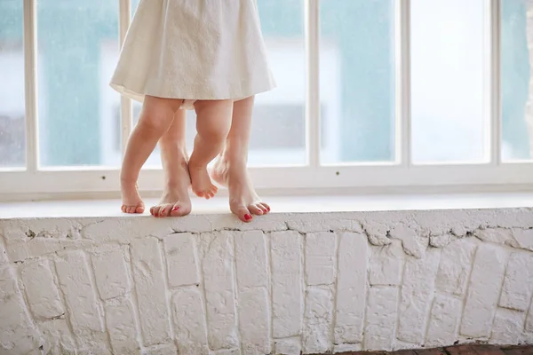 Una giovane madre insegna alla sua figlioletta a camminare. Primo passo del bambino — Foto Stock