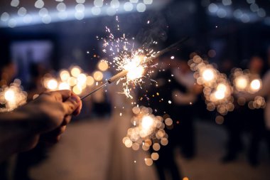 Erkeklerin elindeki Bengal ışıkları arka plandaki Noel ağacı ışıklarında birbirlerini ateşe verdiler.