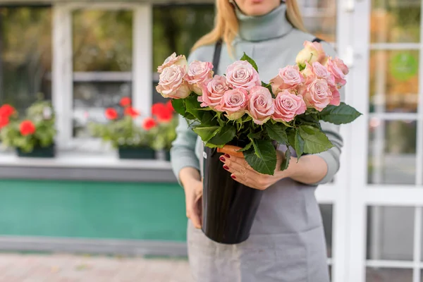 Florist shop in daylight. A woman holds a beautiful bouquet of flowers. Florist with her work. Stylized tender photo