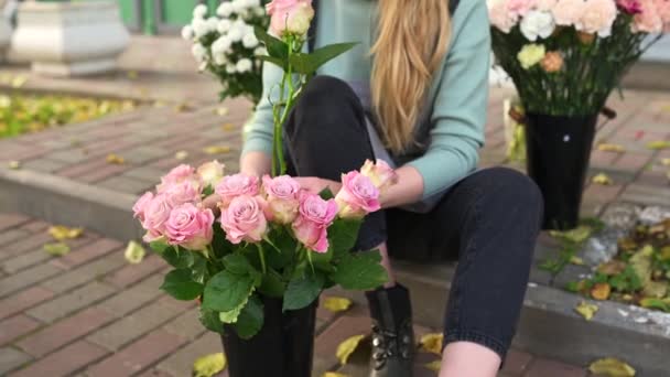 一位女花匠坐在她商店的门口，四周环绕着鲜花。商界妇女 — 图库视频影像