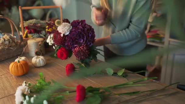 Trabajando en floristería. Florista profesional está creando enorme hermoso ramo de rosas blancas frescas, lirios amarillos y hojas verdes. — Vídeos de Stock