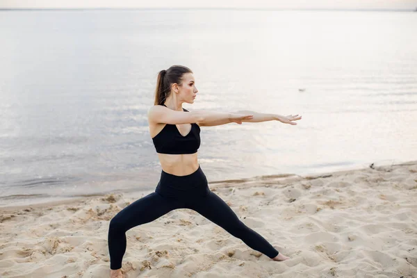 Vacker kvinna som gör morgonövningar på stranden. Yoga meditation vid havet. Vacker soluppgång. Yoga poser — Stockfoto