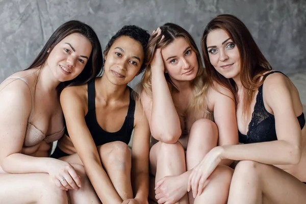 Vier multi-etnische vrouwen in ondergoed poseren op grijs, lichaam positiviteit concept. Kopieerruimte — Stockfoto