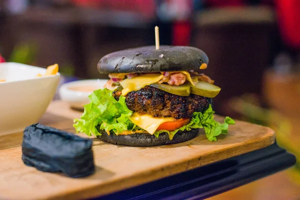 Black burger on wooden board. Toned picture — Stock Photo, Image