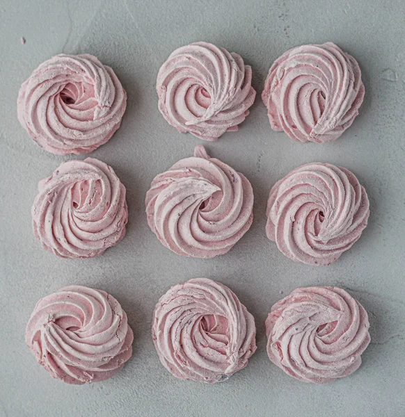 Meringue marshmallow marshmallows lined up in a square on a light background. Mortgage the apartment. The view from the top. Pink sweet homemade marshmallow or marshmallow. Colorful meringues on a whi