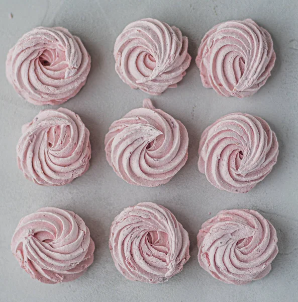 Meringue marshmallow marshmallows lined up in a square on a light background. Mortgage the apartment. The view from the top. Pink sweet homemade marshmallow or marshmallow. Colorful meringues on a whi