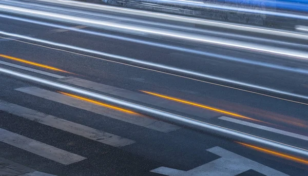 pedestrian crossing at night in the blue light. pedestrian lanes on wet asphalt in neon lights. Smeared lights from cars in motion