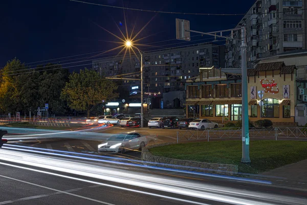 Krasnodar, Rusia - 29 de junio de 2019: cruce peatonal por la noche en la luz azul. carriles peatonales sobre asfalto mojado en luces de neón. Luces manchadas de coches en movimiento — Foto de Stock