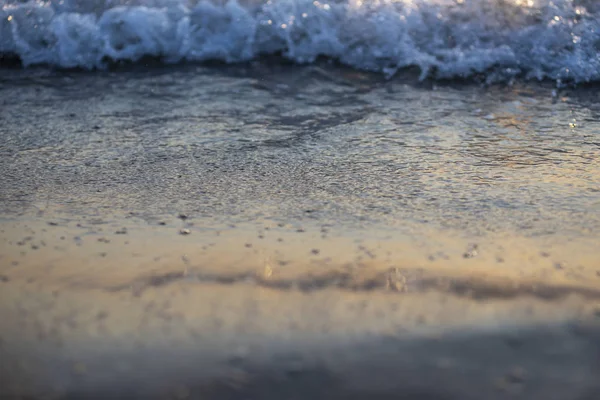 Vagues de mer brillantes sur la plage de sable à la lumière du coucher du soleil — Photo