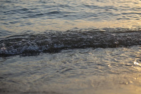 Brillanti onde del mare sulla spiaggia di sabbia alla luce del tramonto — Foto Stock