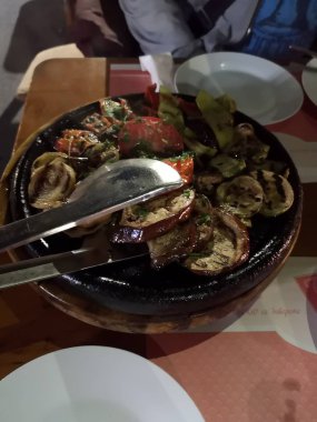 İki beyaz tabaklar ve overlaying için maşa arasında masadaki kızarmış kaba kesim sebze ile pan