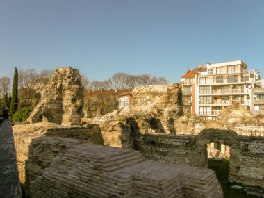 Kemerler ve sütunlarla modern evler ve mavi gökyüzü arka planı zemin seviyesinin altında Antik bir taş yapı kalıntıları