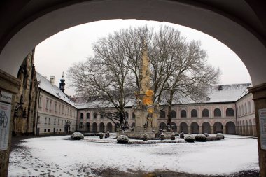 İki katlı evler ile bir colonnade ve çitlerle çevrili bir anıt ortasında çıplak ağaçlar ile üç tarafı çitle çevrili karla kaplı avluya kemer görüntülemek