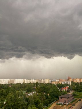 Yeşil ağaçlar ve düşük evler ile şehir üzerinde düşük gri Cumulonimbus yağmur bulutlar