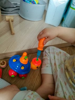 Küçük bir çocuk yerde oturan ve çocuk tasarımcı-kaplumbağa bir tornavida ile vidaları sökme