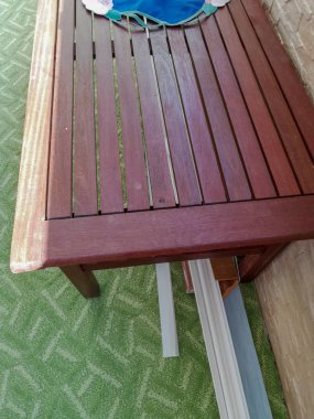 Altında yatan yeşil halı ve taban tahtaları üzerinde ahşap çıtalar masanın bir parçası