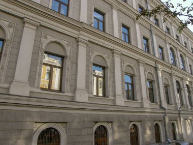 Gri taş bir evin Camlarına yansıyan sarı bir bina