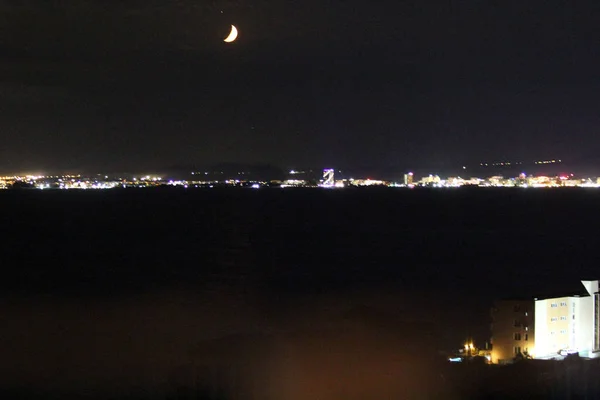 夜空に明るい月と湾を渡る街のライトの眺め — ストック写真