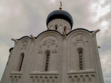 Gri gökyüzüne karşı oyulmuş taş figürler ve sütunlarla dolu beyaz, eski bir kilise.