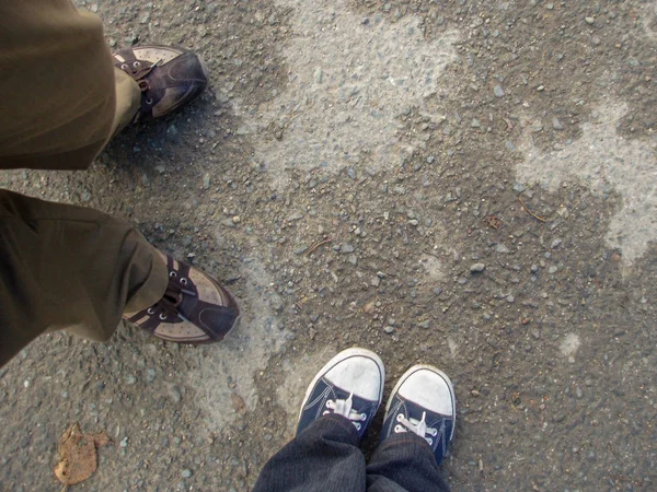 Spor ayakkabılarıyla kaldırımda duran iki çift ayaktan oluşan üst manzara.
