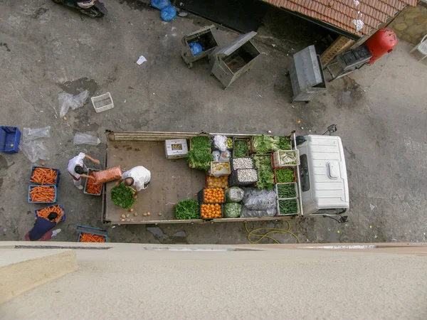 一辆装有一箱箱蔬菜和搬运工的卡车在后院垃圾箱旁边卸下的照片 — 图库照片
