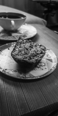 Bir parça kek renkli bir tabakta bir fincan çayın yanında.