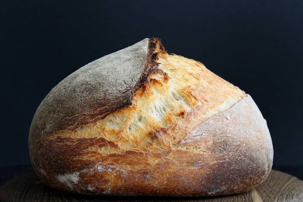 Источниковый хлеб на деревянной доске на черном фоне
