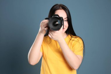 Kadın fotoğrafçı ile renk arka plan üzerinde profesyonel fotoğraf makinesi