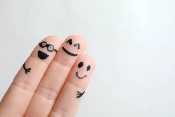 Fingers with drawings of happy faces against light background. Unity concept