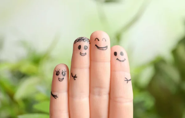 Fingers with drawings of happy faces against blurred background. Unity concept